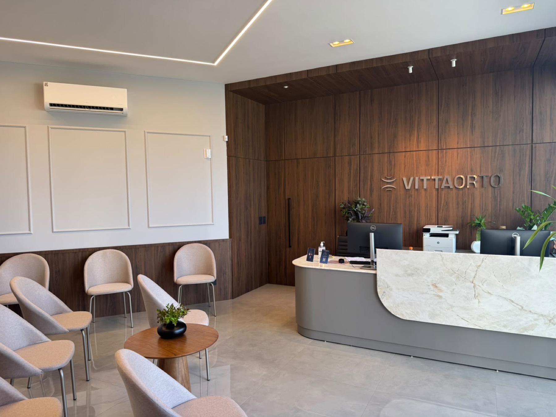 Recepção da Clínica VittaOrto em Concórdia, com painel de madeira e balcão em mármore